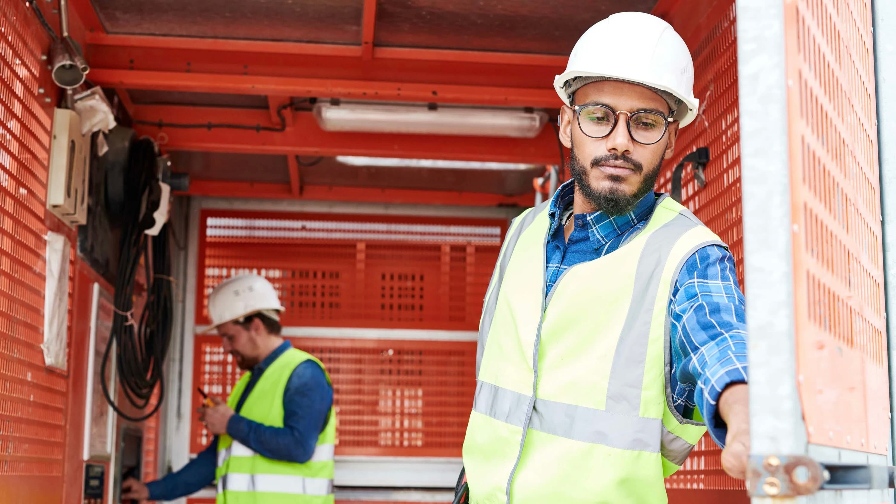 Two men in safety equipment working in the field.