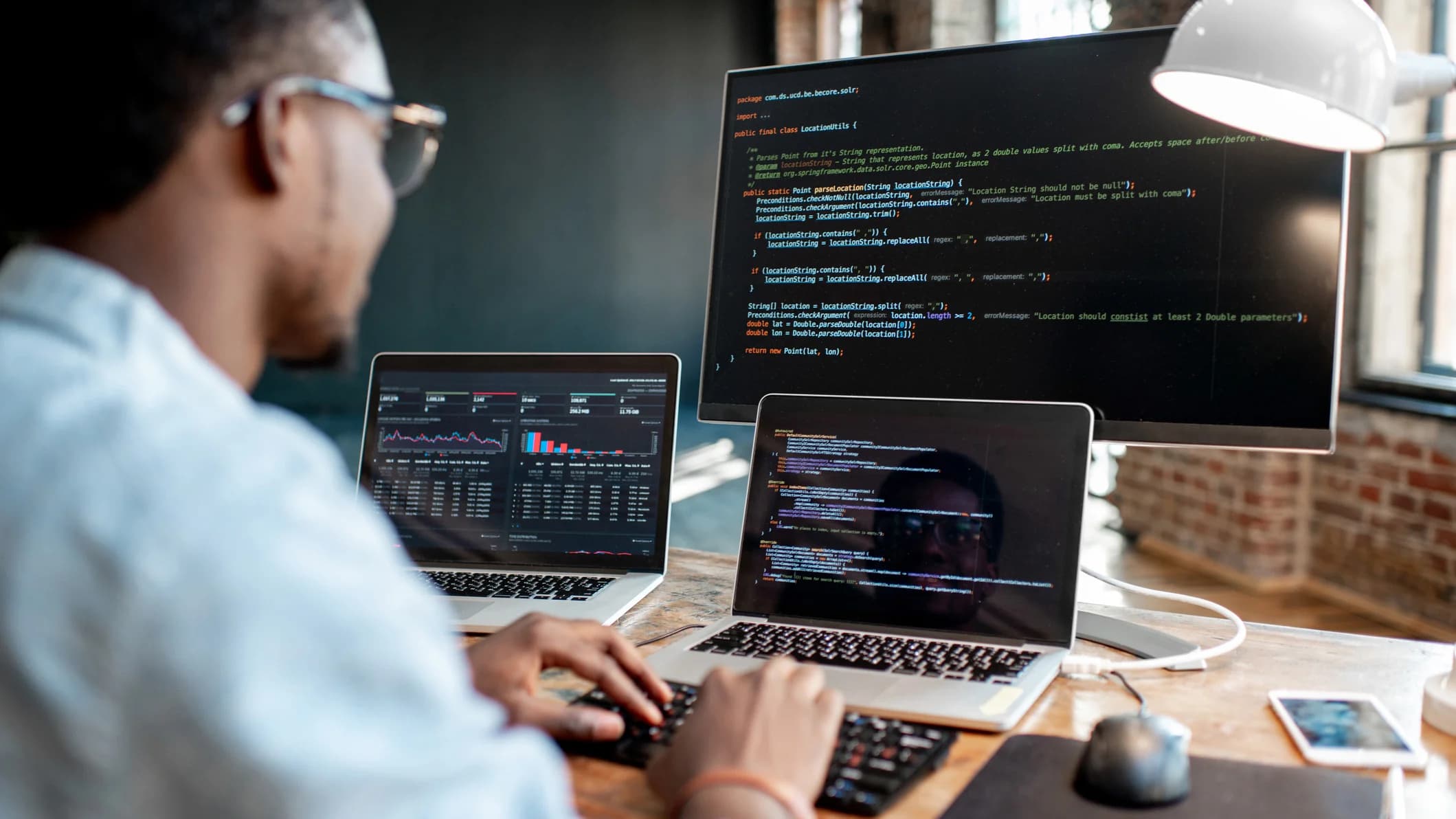 A man looking a multiple screens displaying code